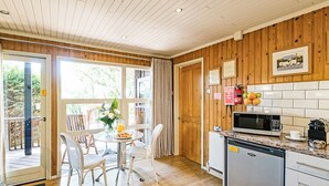 A kitchen with wooden walls, a dining table with chairs, a microwave, and a refrigerator. - Stylish open plan lodge with king-size four poster bed. (Harrogate)