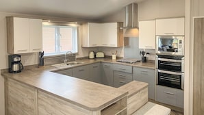 Una cucina moderna con isola centrale, elettrodomestici in acciaio inossidabile e mobili in legno chiaro.