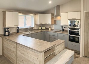 A modern kitchen with a central island, stainless steel appliances, and light wood cabinetry.