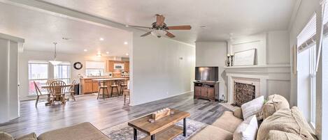 A spacious living room with a fireplace, a dining area, and a kitchen in the background.
