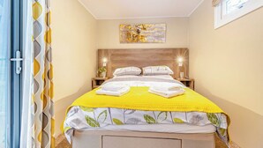 A bedroom with a bed, bedside tables, a wall art piece, and a window. - Rowan Boutique Lodge (Aughton)