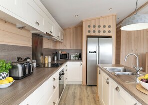 A modern kitchen with white cabinets, a stainless steel refrigerator, a microwave, and a built-in oven.