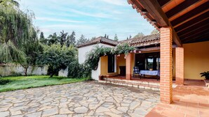 Una casa con un patio de piedra, un porche cubierto y fachada de ladrillo.