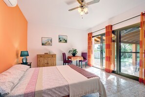 Un dormitorio con cama, escritorio, silla, lámpara y ventilador de techo.