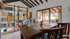 Un comedor con una mesa de madera, sillas y una estantería llena de libros.