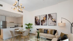 Uma sala de estar moderna com uma mesa de centro de vidro, um sofá e um espaço de jantar com cadeiras.