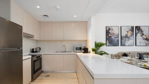 Uma cozinha moderna com eletrodomésticos de aço inoxidável, uma ilha central e um espaço de refeições com sofá e mesa.