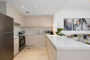 Una cocina moderna con electrodomésticos de acero inoxidable, una isla central y un comedor con sofá y mesa.