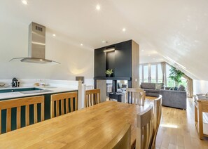 A modern kitchen with a wooden dining table, a built-in stove, and a large window overlooking a balcony.
