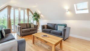 Ein geräumiges Wohnzimmer mit zwei Sofas, einem Holztisch und einem großen Fenster mit Vorhängen.