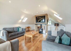 Una sala de estar moderna estilo loft con televisor de pantalla plana, piso de madera y chimenea empotrada.