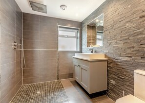 A modern bathroom with a shower, a sink, and a toilet.