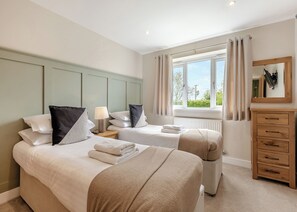Habitación de hotel con dos camas, una cómoda, un ventanal con cortinas y un espejo.