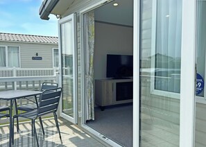 A room with a sliding glass door leading to an outdoor deck, a television, and a cabinet.