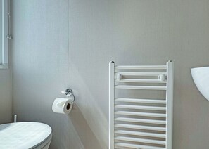 A bathroom with a toilet, a towel rack, and a wall-mounted radiator.