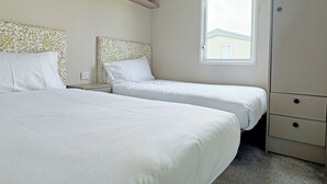 Une chambre avec deux lits, une fenêtre donnant sur un beau paysage, une table de chevet et une armoire.