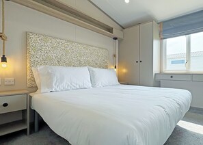 Un dormitorio con una cama grande, mesitas de noche, cabecera con diseño de mosaico y una ventana con persianas.