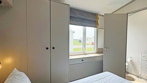 Une chambre à coucher avec un lit, une fenêtre donnant sur un beau paysage, une armoire et un radiateur.