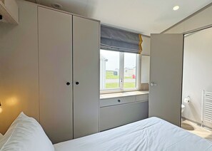 A bedroom with a bed, a window with a view, a wardrobe, and a radiator.