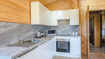 A compact kitchen with white cabinets, a stainless steel sink, a microwave, a toaster, and an oven.