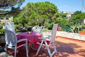 Une terrasse extérieure avec une table et des chaises, entourée de verdure et donnant sur un quartier résidentiel.