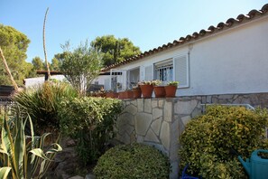 A house with a stone wall, potted plants, and a clear blue sky. - Holiday Home 'Andrea' with Mountain View, Private Terrace and Wi-Fi (Tossa de Mar)