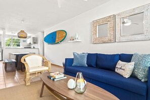 Un salon moderne avec un canapé bleu, un fauteuil en osier et une table basse en bois.