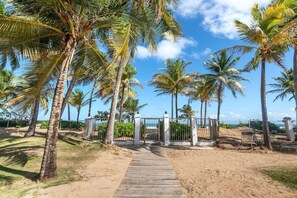 A pathway leading to a gated area with palm trees and a clear sky. - Cayo La Mancha | Beachfront living in Rio Grande (Río Grande)