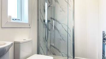 A modern bathroom with a glass-enclosed shower, a toilet, and a sink.