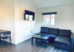 A modern living room with a sofa, a coffee table, a TV mounted on the wall, and a window with a view. - 2 bedroom accommodation in Kilwinning (Kilwinning)