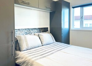 A bedroom with a bed, a headboard, and a window.