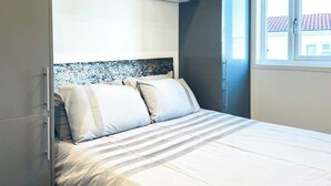 A bedroom with a bed, a headboard, and a window.