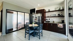 A modern kitchen with dark cabinets, a marble countertop, and a dining area with a table and chairs.