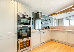 A modern kitchen with built-in appliances, a wooden countertop, and a window providing natural light.