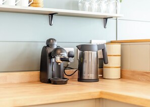 A coffee maker, a kettle, and a sugar container on a kitchen counter. - Luxurious lodge with vaulted ceilings and a welcoming feature fireplace. (Glastonbury)