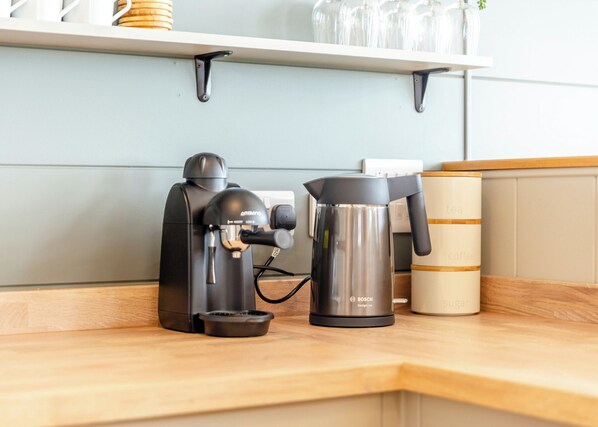 Eine Kaffeemaschine, ein Wasserkocher und ein Zuckerbehälter auf einer Küchenarbeitsplatte.
