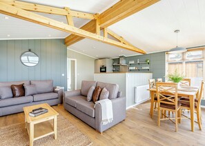 A cozy living room with a sofa, coffee table, and dining area with chairs and a table. - Luxurious lodge with vaulted ceilings and a welcoming feature fireplace. (Glastonbury)