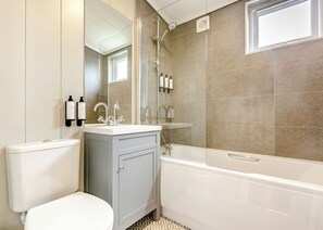 A bathroom with a toilet, a sink, a mirror, a shower, and a bathtub. - Luxurious lodge with vaulted ceilings and a welcoming feature fireplace. (Glastonbury)