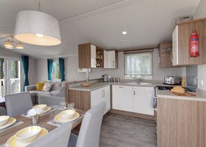 A modern kitchen with a dining area, wooden cabinets, and a fire extinguisher.
