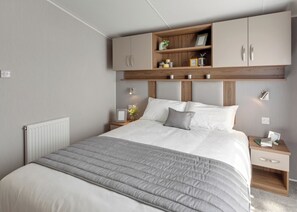 A modern bedroom with a bed, a nightstand, a wooden headboard, and built-in storage cabinets.