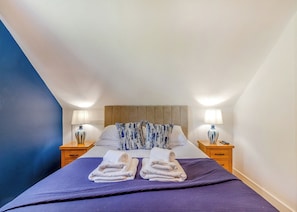 A hotel room with a bed, two bedside tables, a headboard, and a blue accent wall. - Outstanding and beautifully presented first floor apartment. (Glastonbury)