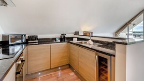 A modern kitchen with built-in appliances, a sink, and a window overlooking a landscape. - Outstanding and beautifully presented first floor apartment. (Glastonbury)