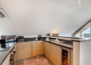 A modern kitchen with built-in appliances, a sink, and a window overlooking a landscape.