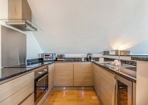 A compact kitchen with a microwave, toaster, and coffee maker, wooden cabinets, and a granite countertop.