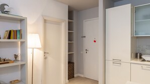 Une salle de bain moderne avec un lavabo blanc, un miroir et un meuble, un espace douche, ainsi qu'une étagère avec des livres et une lampe.