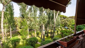Un balcon donnant sur un jardin luxuriant et de grands arbres.