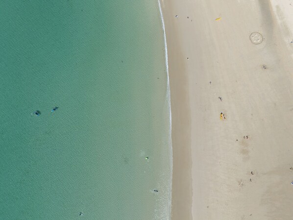 Vista aérea de una playa con agua turquesa cristalina y una orilla arenosa.