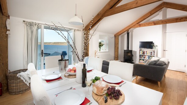 A dining area with a table set for four, a fireplace, a sofa, and a bookshelf.