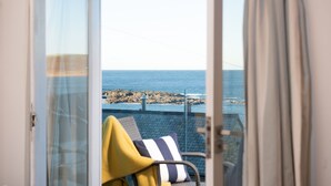 A room with a view of the sea through a glass door.