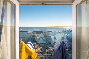 A balcony with wicker furniture, a yellow towel, and a blue towel.